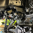 Undercarriage view of a vehicle showing the front suspension of an SB Suspension Kit and steering system components.