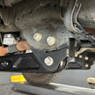 Undercarriage view of a vehicle showing the front suspension of an SB Suspension Kit and steering system components.