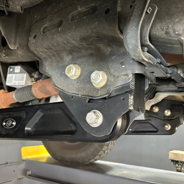 Undercarriage view of a vehicle showing the front suspension of an SB Suspension Kit and steering system components.