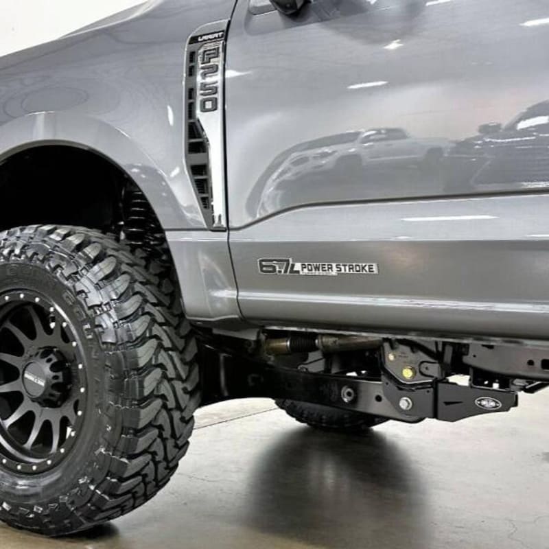 A silver 2023+ Ford power stroke truck with a 2.5 inch lift kit, showcasing the raised front and the new aftermarket wheels and tires.
