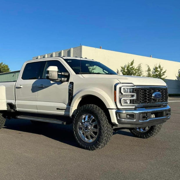 A white 2011-2022 F450 truck with an S&B 2.5 inch lift kit, including a front bumper, grille, and large tires for off-road use.