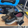SB Filters JLT Cold Air Intake for 2017-2024 Camaro ZL1 6.2L on a wooden table with a blue car in the background