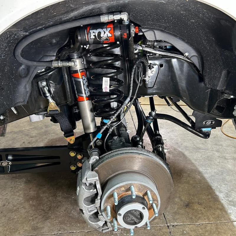 Undercarriage view of a vehicle showing the front suspension of an  SB Fully Loaded Kit For 2011-2016 F450  and steering system components.