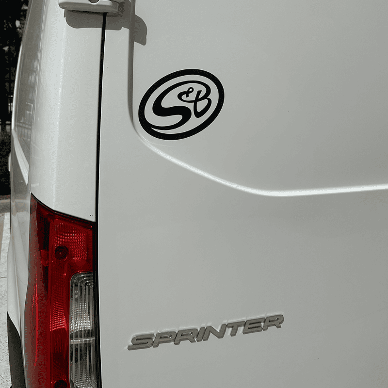 White van with a decal of S&B logo text on the back