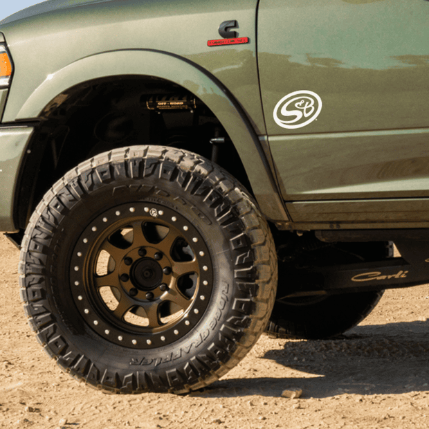 A green truck with a decal of S&B logo on the fender.