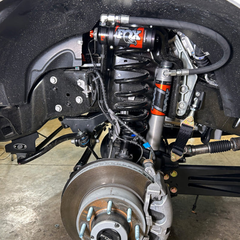 Close-up of an Undercarriage view of a vehicle showing the front suspension of an  SB Aluminum Beam Arms (2005-2022 Super Duty)  and steering system components.